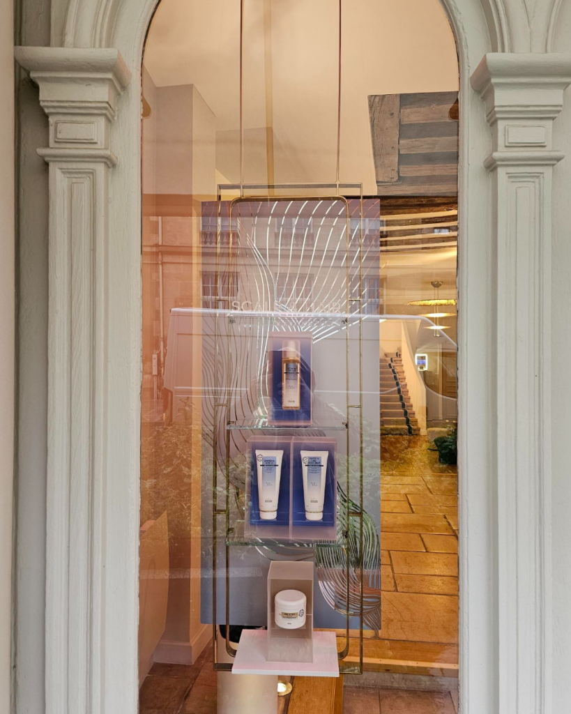 Reflets argentés et jeux de lumière dans une scénographie de vitrine pour une marque de cosmétiques.