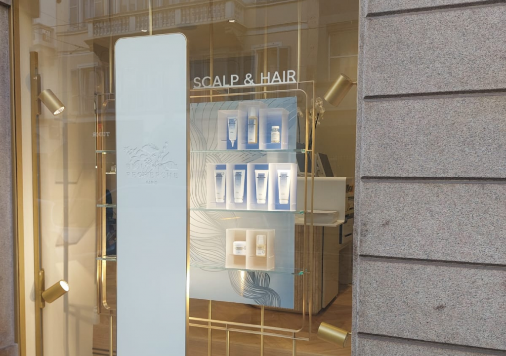 Vitrine de lancement pour une marque de cosmétiques de luxe mettant en valeur une nouvelle gamme de soins capillaires.