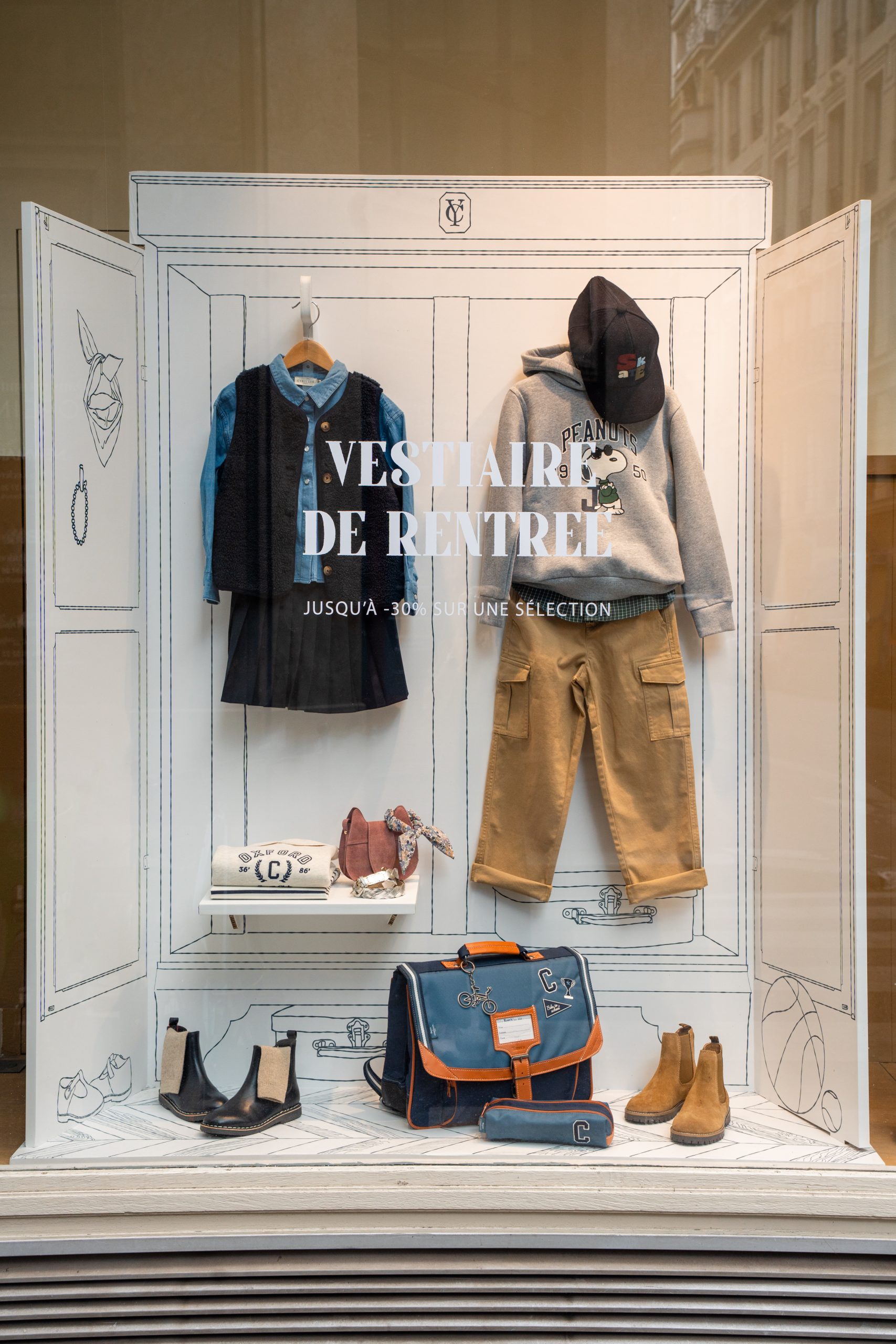 Vitrine mode enfant Cyrillus : tenue de rentrée présentée dans une armoire de papier illustrée